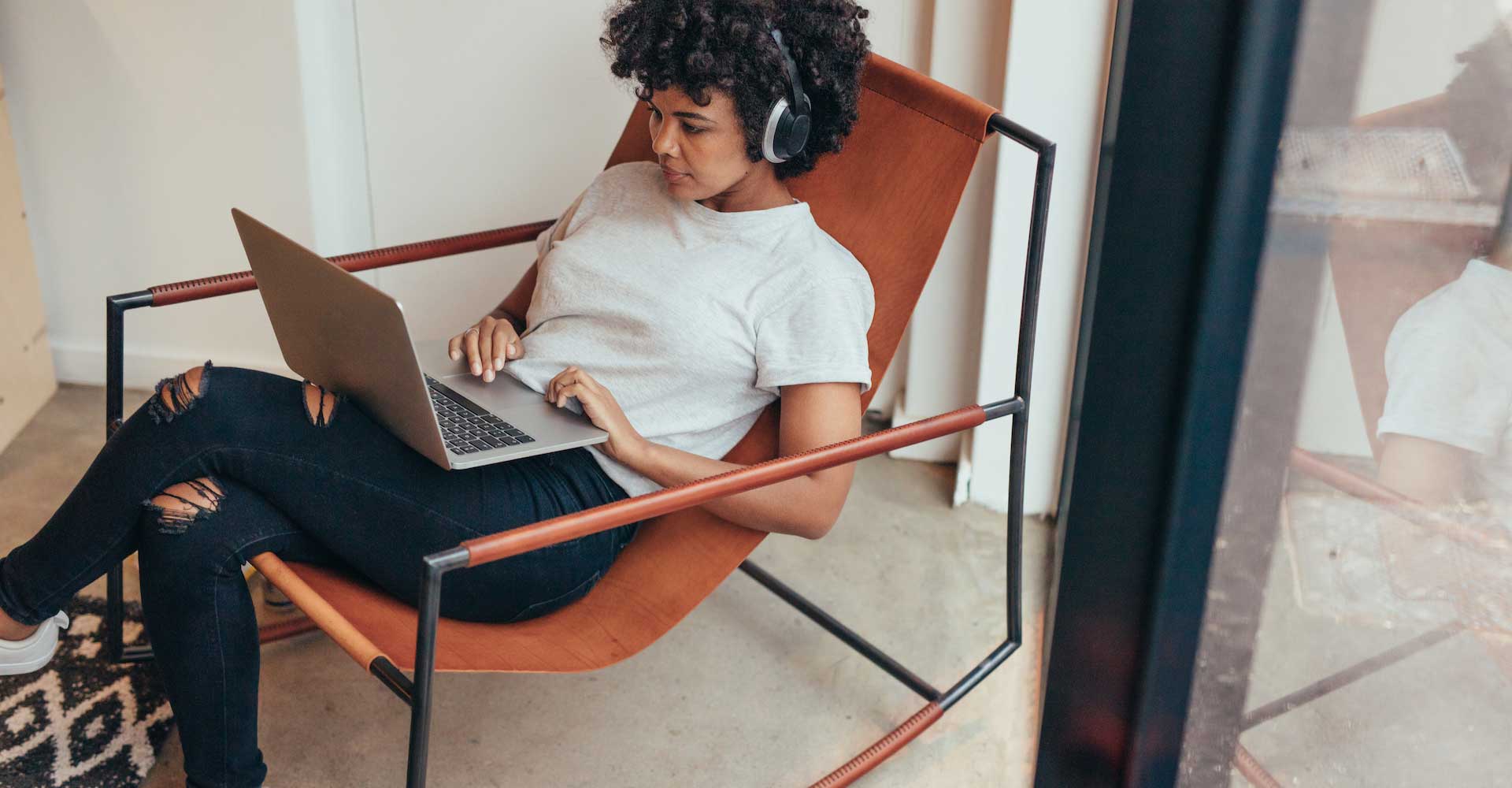 Image of girl sitting relaxed on a chair while working on computer